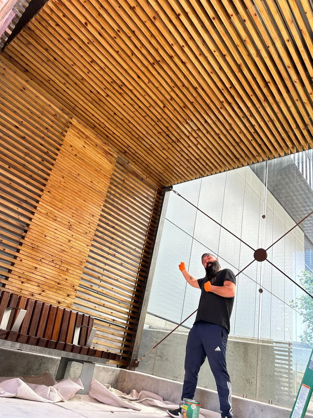 Matthew Demirhan on a job site, painting a cedar slat ceiling